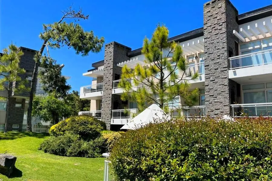 Edificio Manzana Uno con jardín y pinos